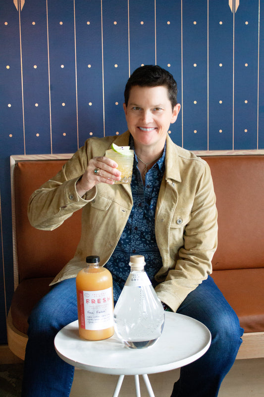 Beach Pace of Big Brothers Big Sisters Columbia NW. Smiling with a Free Fallin' cocktail next to a bottle of Freeland Dry Gin.