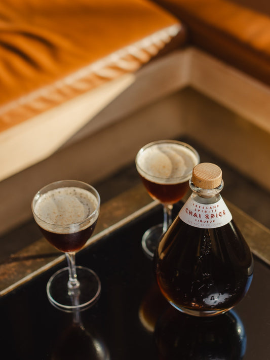 Bottle of Freeland Chai Spice Liqueur in collaboration with Smith Teamaker - next to two espresso martini inspired cocktails